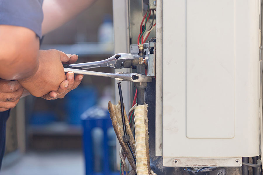 Technician tightening AC unit connections